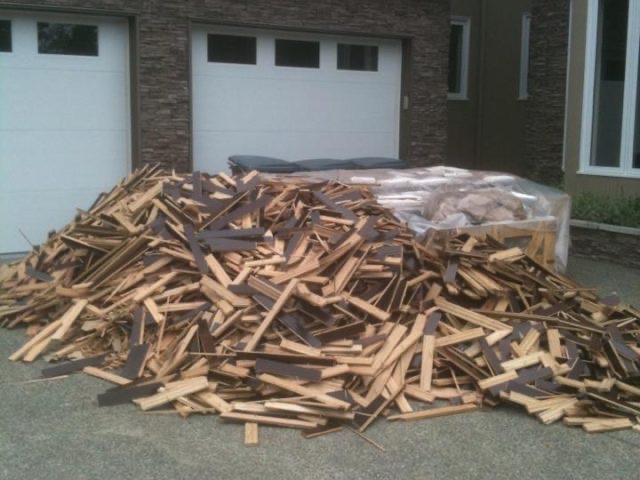Hardwood planks stacked loose on a dark floor before installation