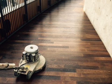 Floor machine at work refinishing dark-stained wood stairs